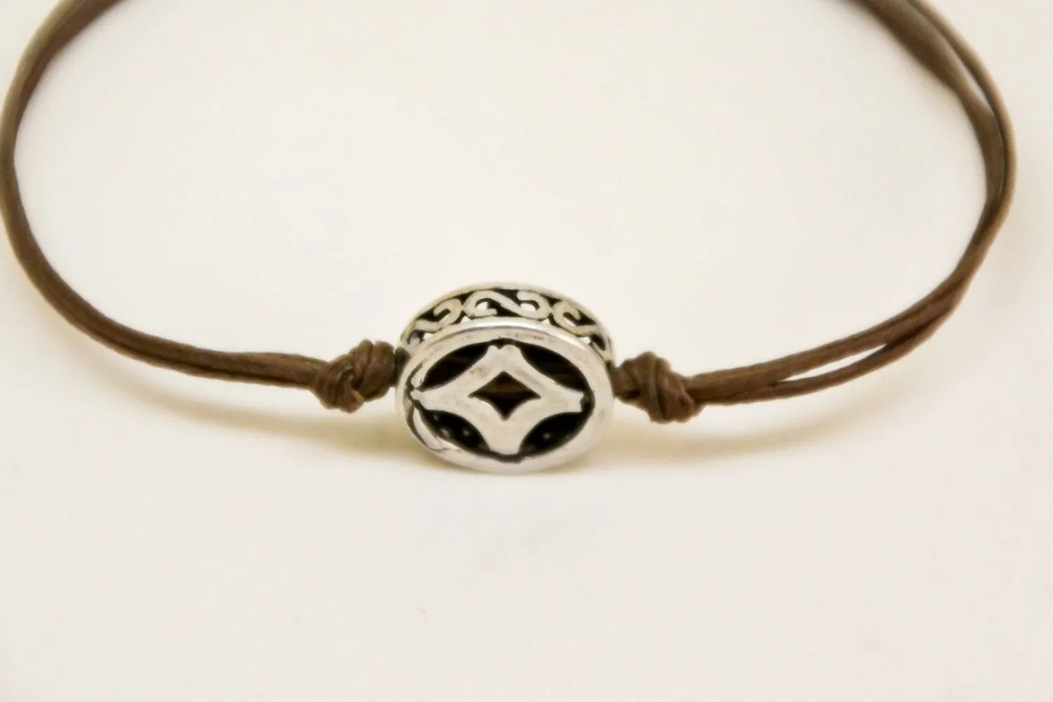 Brown cord bracelet with decorated silver circle bead charm